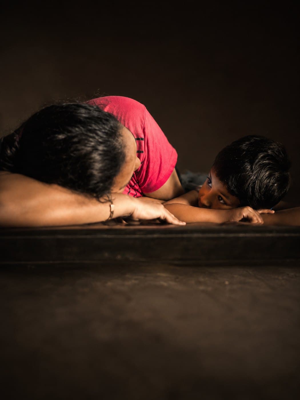 A parent lying face to face with her child, sharing a quiet moment of connection