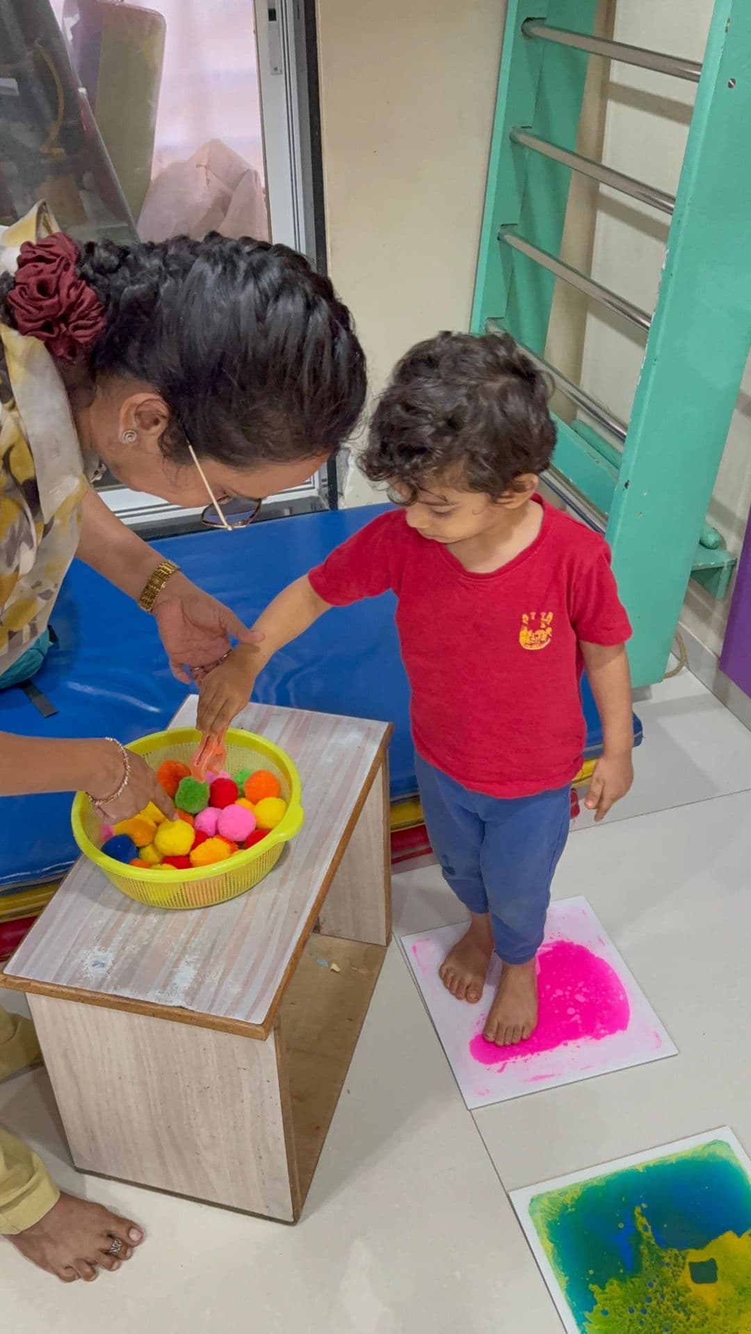 A toddler stepping across colourful sensory floor pads
