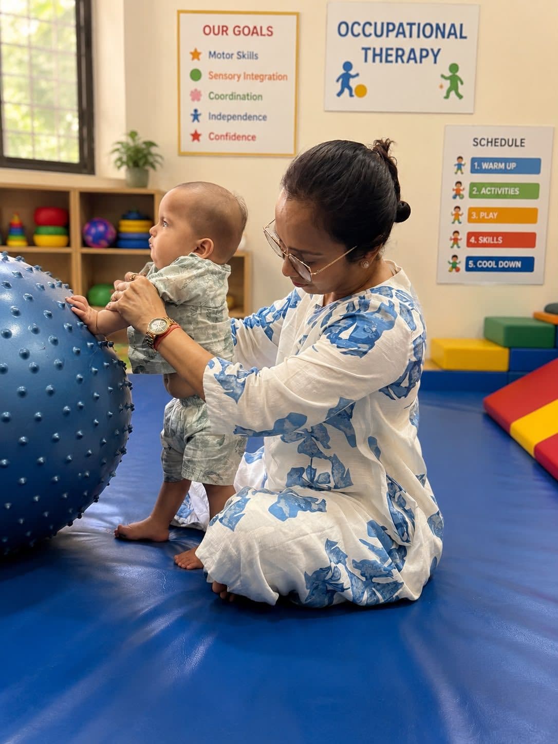 A baby pulling up to stand against a textured therapy ball