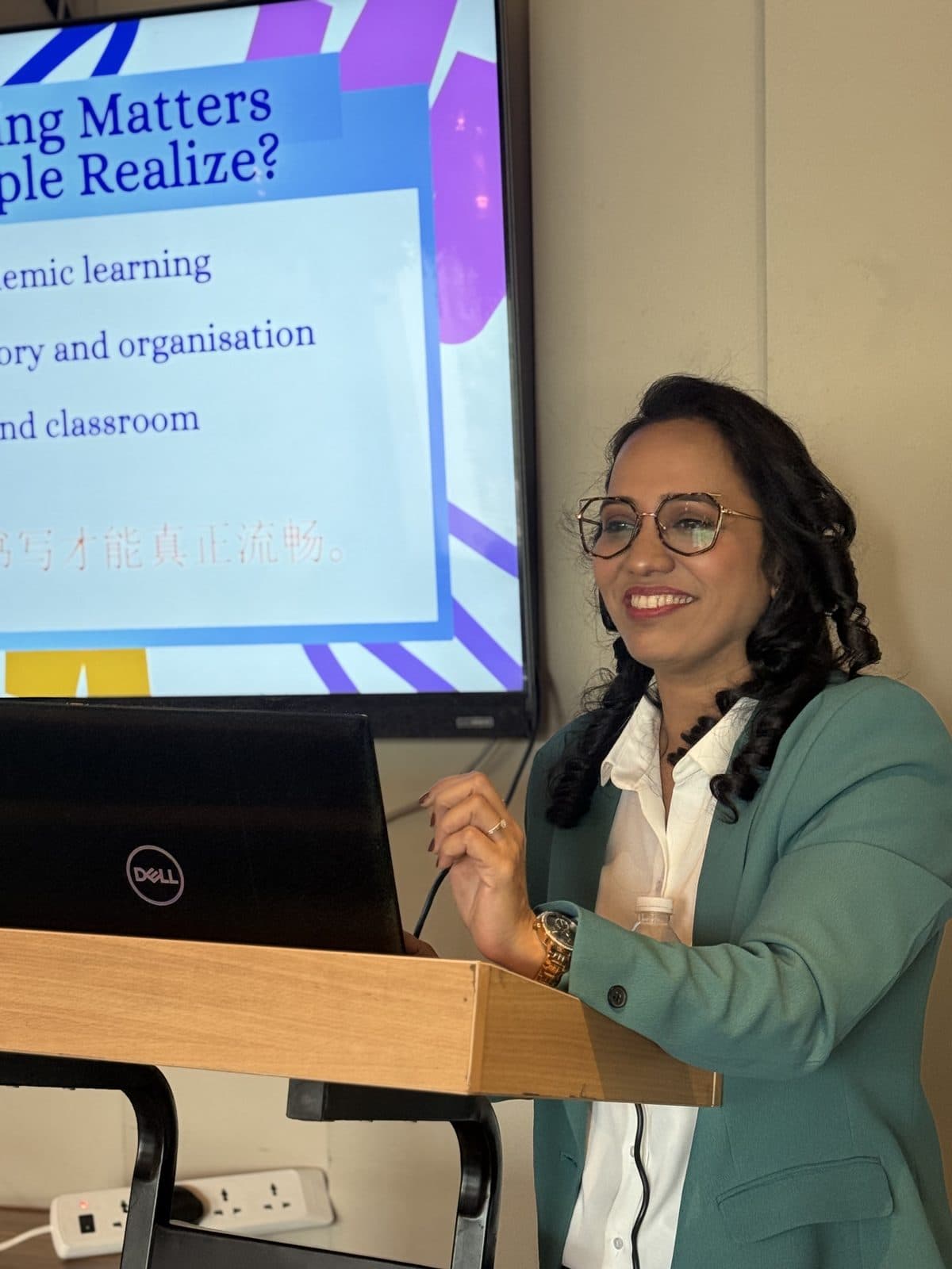 Dr. Sharuja smiling while presenting a handwriting workshop at the podium