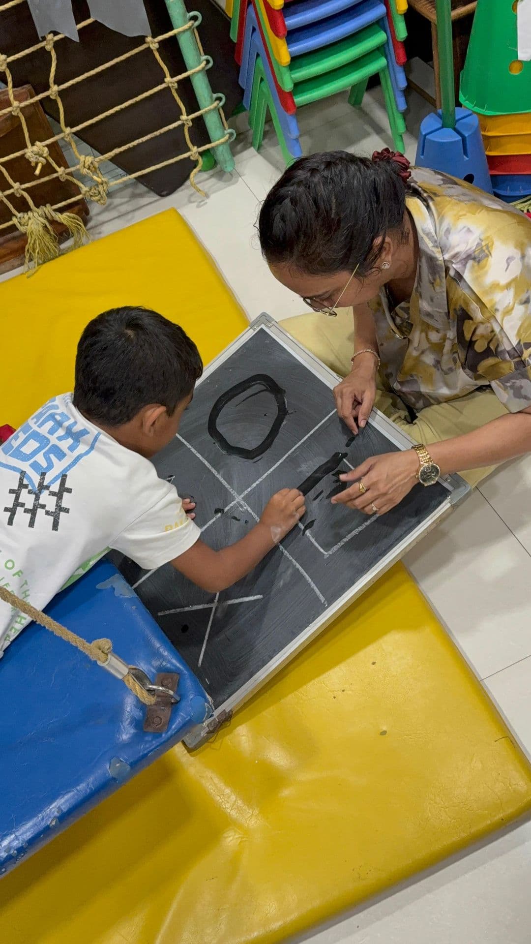 Dr. Sharuja playing a chalkboard game one-on-one with a young boy